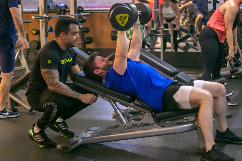 Homem Malhando na academia cim auxílio de personal